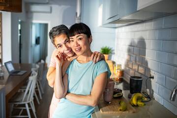 Lesbian couple making healthy organic smoothie together in modern kitchen