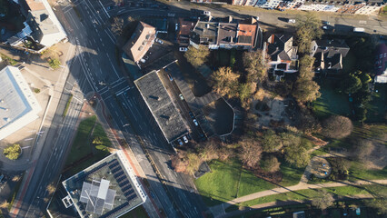 Aerial view of city blocks with red roofs and green areas. The image shows a sunny day, narrow streets and neat houses surrounded by trees. Ideal for illustrating urbanism or architecture.