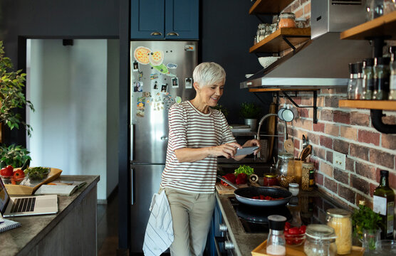 Senior woman cooking healthy meal in modern kitchen