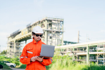Industrial site engineer wearing orange reflective gear, managing scaffolding inspection with a laptop and walkie-talkie, emphasizing expertise in construction safety and project management.