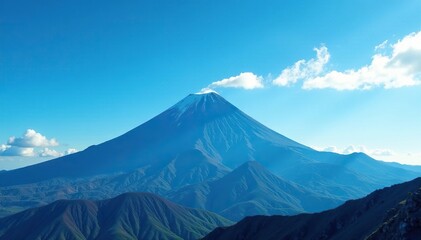 Fototapeta premium Volcanic peak silhouetted against bright blue sky with wispy clouds, blue sky, volcanic peak