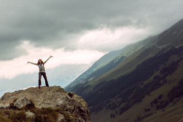 One happy tourist mountaineer on top of a mountain, hands spread to sky