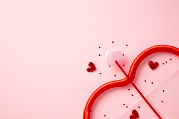 Happy Valentines Day creative layout with cupid bow and arrow with hearts on light pink background. Love, romance concept. Minimal, elegant style.