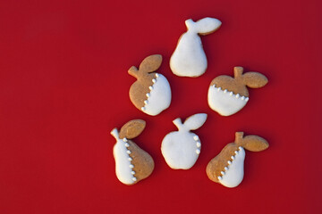 Gingerbread cookies in a shape of apple and pear on a red background, copy space for text