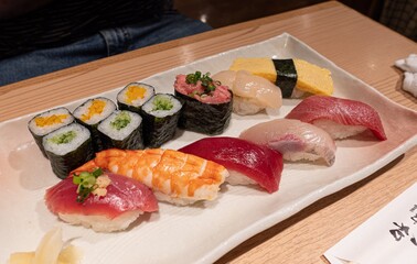 White plate beautifully topped with sushi on a table in Japan subway restaurant