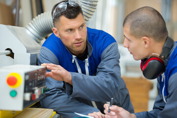 workman explaining how the machinery works to a new-recruit