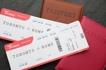 Travel agency. Flight tickets and passports on dark textured table, flat lay