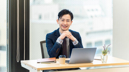 パソコンを使う笑顔の男性ビジネスマン