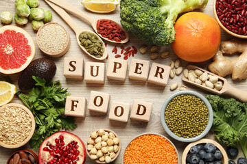 Superfood. Different healthy food products and cubes on wooden table, flat lay
