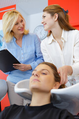 Fototapeta premium trainee hairdresser washing female clients hair under supervision