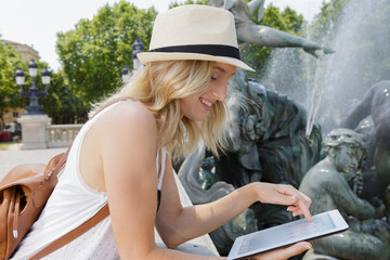 happy woman wearing stylish hat watching movie using tablet computer