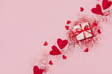 Gift box and red hearts decorated shiny glitter for Valentines Day. Aesthetic modern background in pink color. Top view, flat lay.