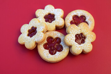 Linzer cookies on a red background, flowers and round shape. Homemade baking
