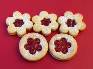 Linzer cookies on a red background, flowers and round shape. Homemade baking