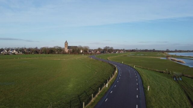 Zalk, the Netherlands - January 8th 2025: Aerial footage of the Dutch village Zalk. The drone is taking of from the dyke and moving towards the Sint Nicolaas church.