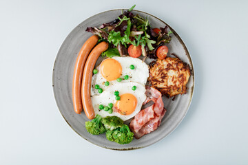 English breakfast with eggs, sausages, bacon and greens