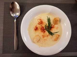 Vertical composition. Creamy cheese soup with croutons and herbs on a wooden background. View from above.