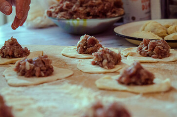 Close-up making dumplings with meat from dough, table background