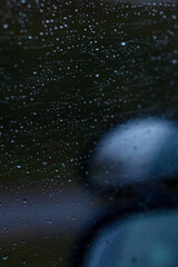 Fototapeta premium Closeup of a cars rearview mirror with raindrops on it