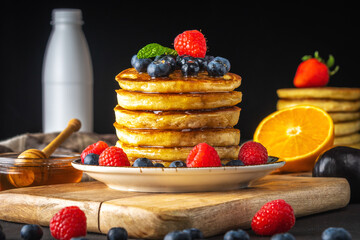 Delicious pancakes with fresh berries on dark background. Food concept.