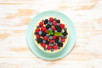 Homemade cake with fresh berries on wooden background.
