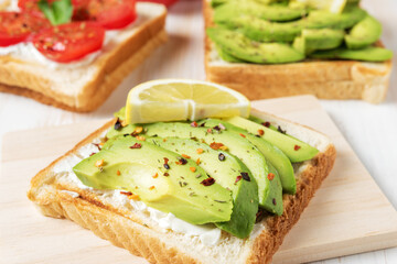 Sliced avocado on toast bread with spices on white wooden background. Food concept.