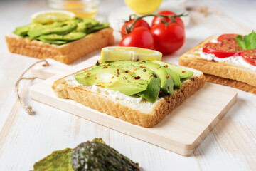 Sliced avocado on toast bread with spices on white wooden background. Food concept.