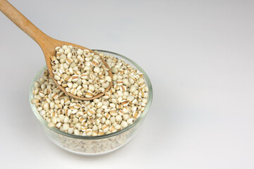 Wood spoon of Job's tears white background.
Adlay or millet in Wooden ladle and 
glass bowl.   Scientific name is Cox lacrima job.
top view.