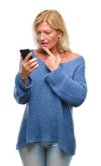 Middle age blonde woman sending message using smartphone over isolated background serious face thinking about question, very confused idea