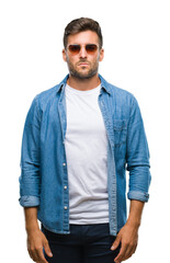 Fototapeta premium Young handsome man wearing sunglasses over isolated background with serious expression on face. Simple and natural looking at the camera.