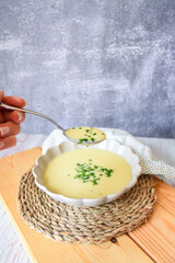 white vegetable cream and a hand holding the spoon. homemade recipe for Vichyssoise 