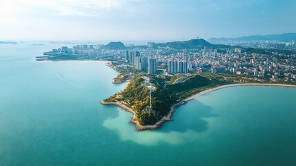 Naklejka premium Aerial view of coastal city skyline, ocean, hills, and green parkland.