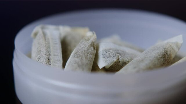 Snus nicotine tobacco close up, pack of tobacco for gum. unhealthy addiction. Man opening box with snus and taking one. 