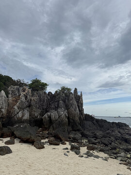 Rocky coastal landscape under cloudy skies at dawn near a quiet beach