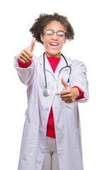 Young afro american doctor woman over isolated background approving doing positive gesture with hand, thumbs up smiling and happy for success. Looking at the camera, winner gesture.