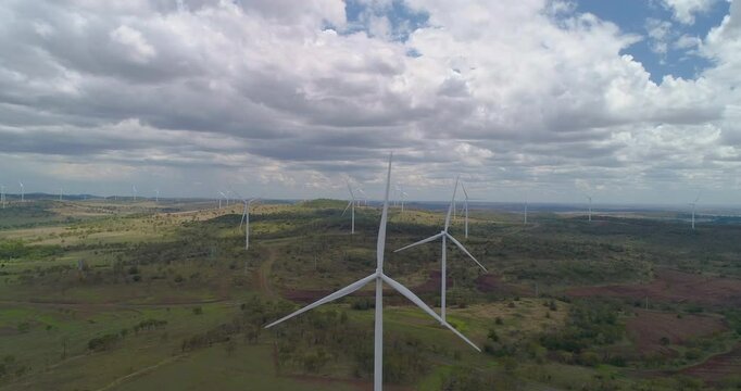 Forward tracking drone view of  Wind Turbines On Green Hills at wind farm, Queensland, Australia