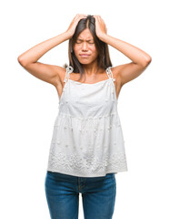 Young asian woman over isolated background suffering from headache desperate and stressed because pain and migraine. Hands on head.