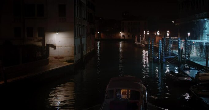 Boat traveling through the canals of Venice during a cold winter night