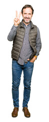Fototapeta premium Middle age handsome man wearing winter vest showing and pointing up with fingers number two while smiling confident and happy.