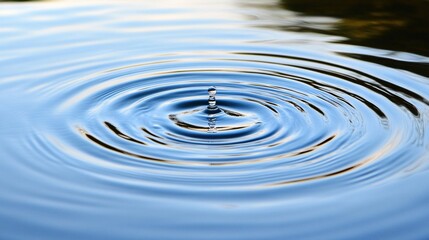Water Droplet Impacting Calm Blue Water Creating Concentric Circles