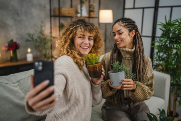 female friends take a self portrait with flower pot with mobile phone