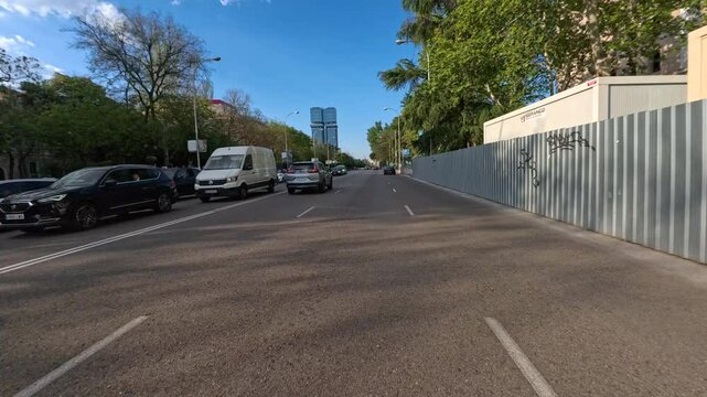 Personal perspective POV of a man driving a motorbike on the Paseo de la Castellana in Madrid on a sunny day from Plaza de Cibeles to Plaza de Emilio Castelar, crossing Plaza de Colon, Madrid, Spain