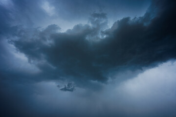 Dramatic storm clouds in blue sky associated with storm, dark, moody weather and looming atmosphere