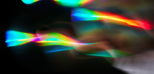Blurred bright rainbow light. Lens or prism dynamic flare. Draving shiny spots. Dark background....