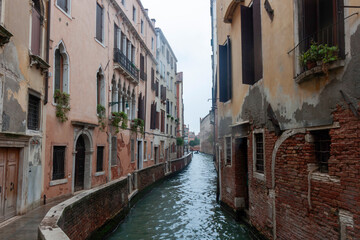 A picturesque view of a narrow canal in Venice, Italy, with reflections of colorful buildings on the water