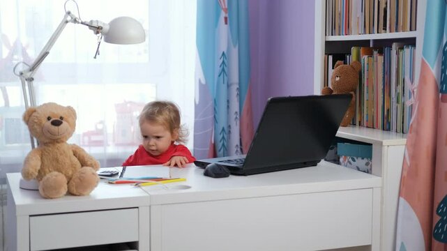 In a cheerful nursery, a cute baby girl using a laptop at her work desk. Surrounded by teddy bears and colorful toys. Freelance and distance work concept