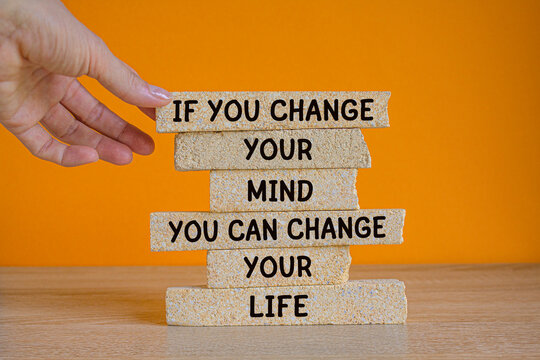 If you change your mind you can change your life. Words on brick blocks on beautiful orange background. Motivational quote to create future. Businessman hand.