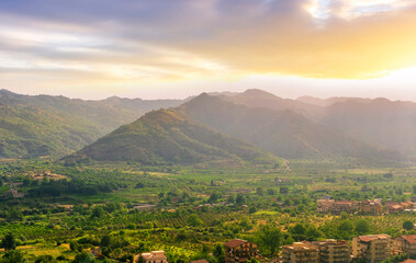 Obraz premium scenic panorama of italian town during sunset with amazing view from above to nice city with picturesque mountain valley landscape and cloudy sky on backdrop