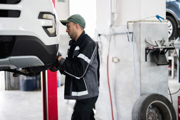Mechanic working on car repair in auto workshop garage