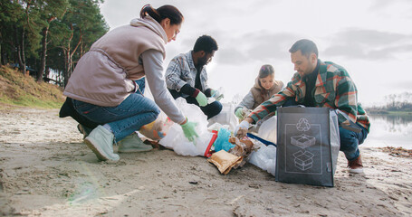 People collectively volunteering in local area. Collecting trash and sorting everything into...